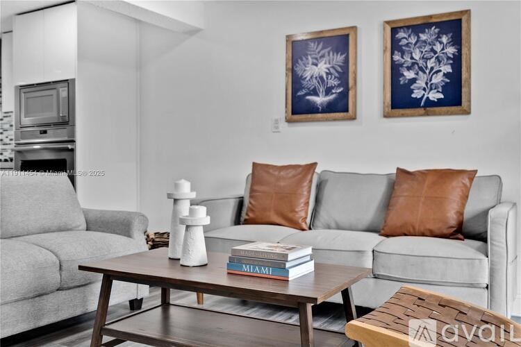 A living room with a grey couch, a coffee table, and two framed pictures on the wall.