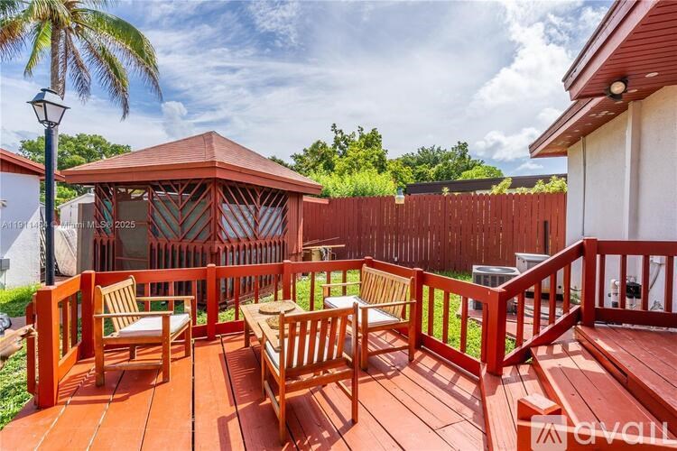 A wooden deck with a gazebo and chairs.