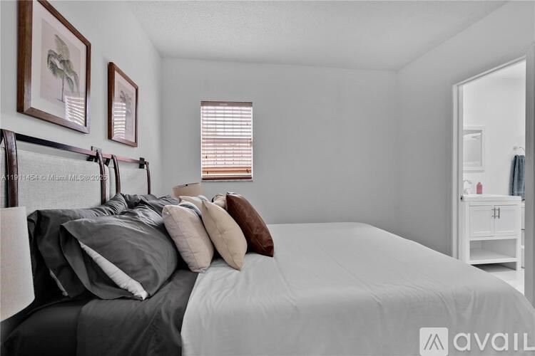 A bedroom with a bed, pillows, and pictures on the wall.