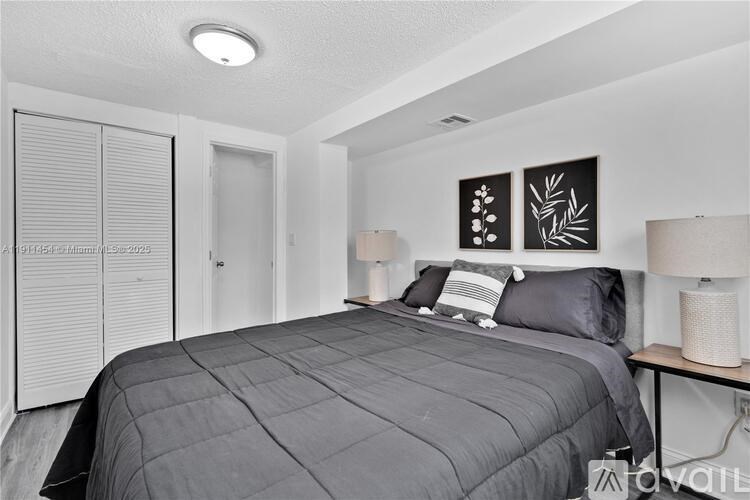 A bedroom with a bed, two lamps, and a painting on the wall.