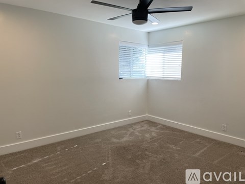 A room with a ceiling fan and a window with blinds.