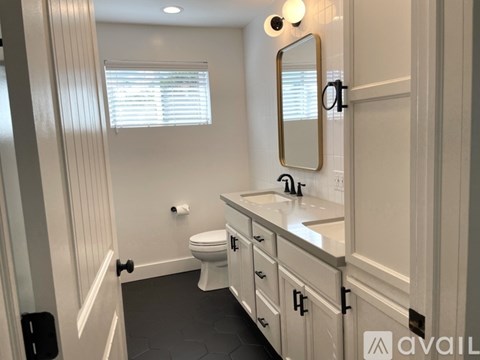 A bathroom with a toilet, sink, and mirror.