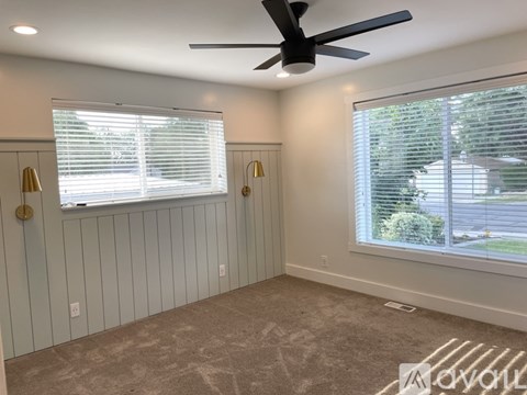 A room with a ceiling fan and two windows with blinds.