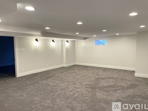 A spacious room with grey carpeting and white walls.