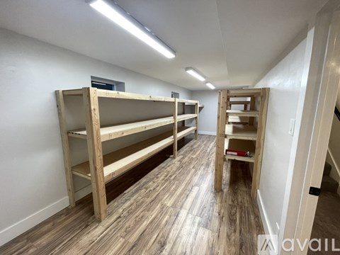 Empty wooden shelves in a room with white walls and wooden flooring.