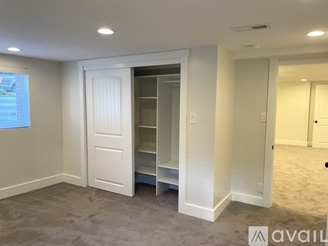 A room with a white door and a window showing a view of a street.