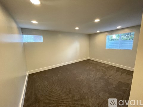 A room with a carpeted floor and a window with blinds.
