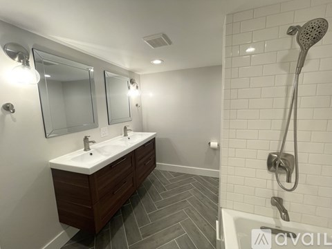 A bathroom with a white sink and a shower with a silver shower head.