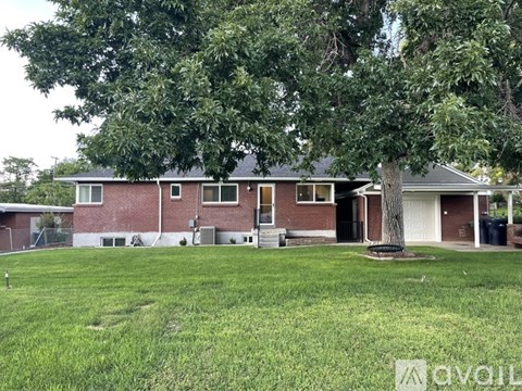 A house with a red brick exterior and a large tree in front.