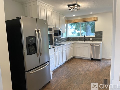 A kitchen with a black refrigerator and white cabinets.