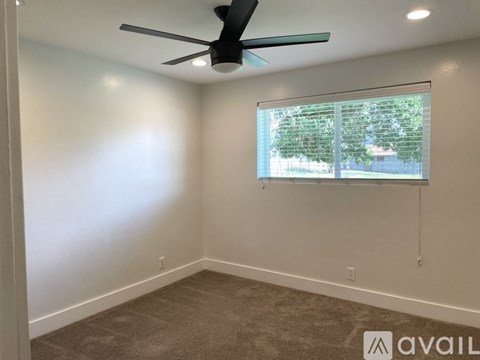 A room with a ceiling fan and a window with blinds.