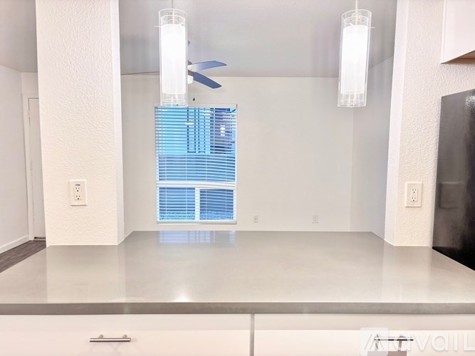 A modern kitchen with a white countertop and a ceiling fan.