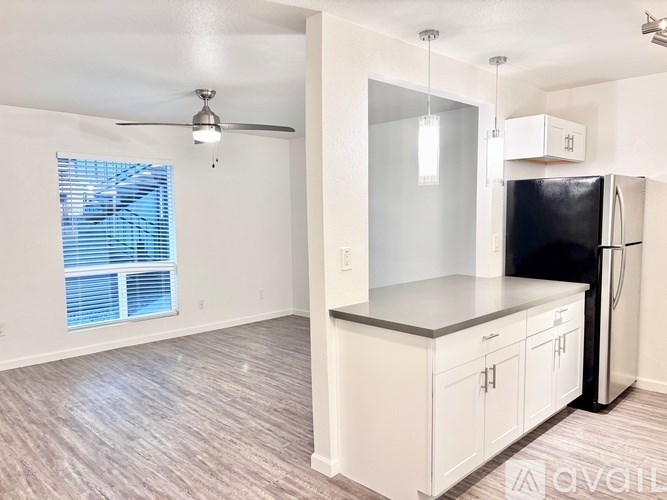 A kitchen with white cabinets and a black refrigerator.