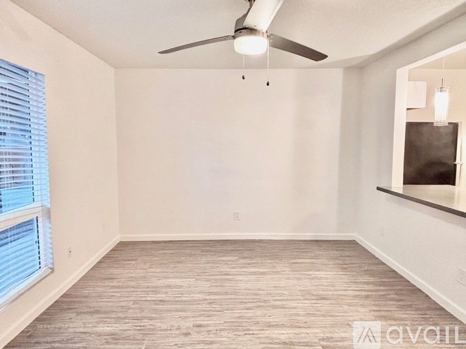A room with a ceiling fan and a window with blinds.