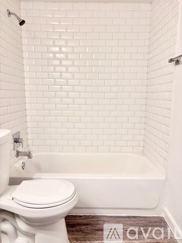 A white toilet sits next to a white bathtub in a bathroom with white tiles.