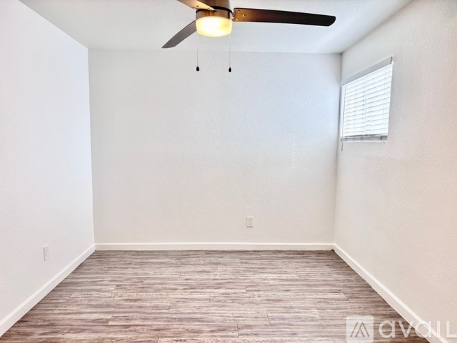 A room with a ceiling fan and wooden flooring.