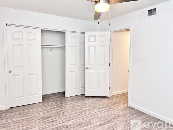 A room with a ceiling fan and three doors.