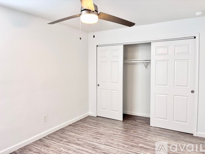 A room with a ceiling fan and a white door.