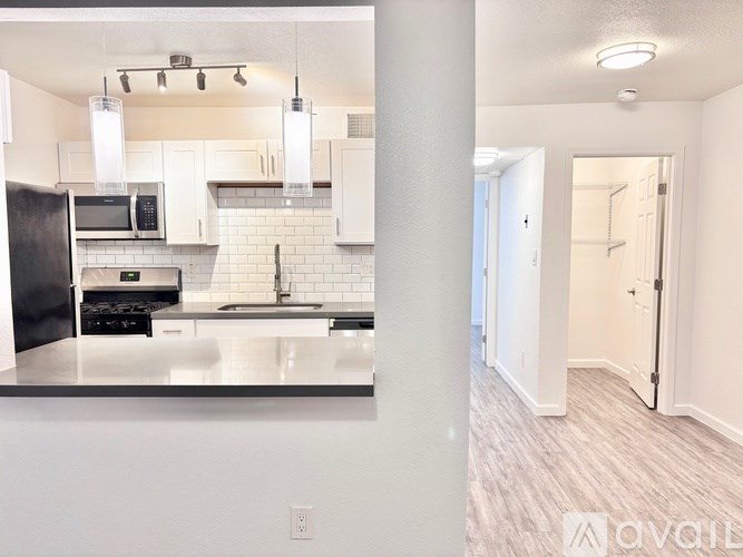 A kitchen with white cabinets and a black fridge.