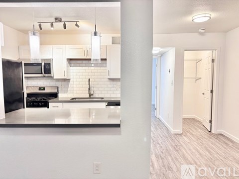 A kitchen with white cabinets and a black fridge.
