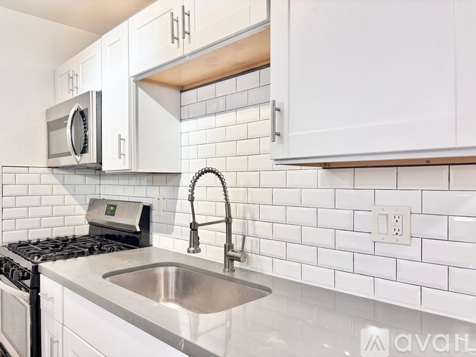 A kitchen with white cabinets and a stainless steel sink.