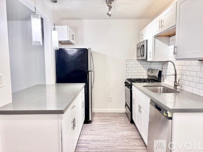 A kitchen with white cabinets and a black refrigerator.
