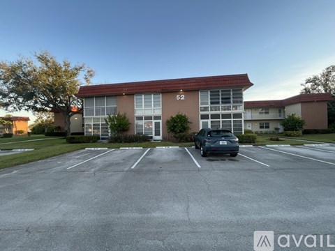 A car is parked in a parking lot in front of a building with the number 52 on it.