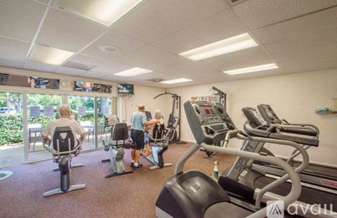 A gym with people exercising and a TV mounted on the wall.