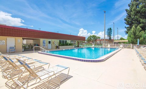 A pool with sun loungers and a building in the background.