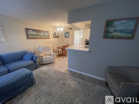 A living room with a blue couch and a painting on the wall.