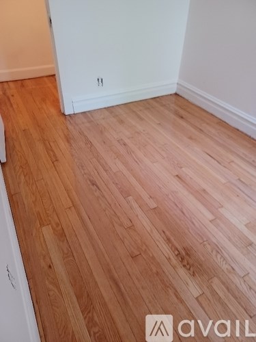 A room with wooden flooring and a white wall.