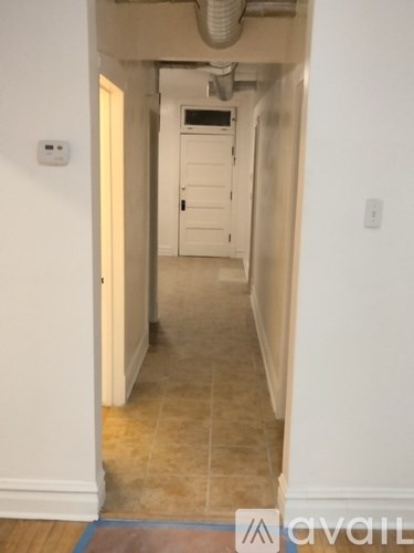 A hallway with a door at the end and a tiled floor.