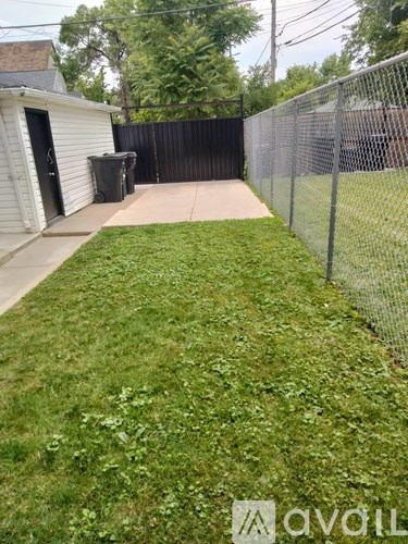 A backyard with a fence and a green lawn.