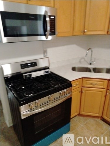 A kitchen with a stove, sink, and cabinets.
