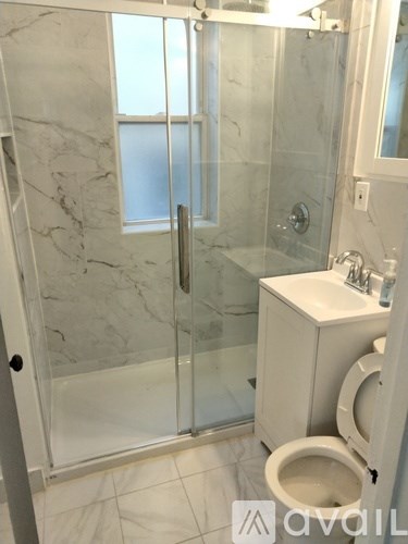 A bathroom with a toilet, sink, and walk-in shower.