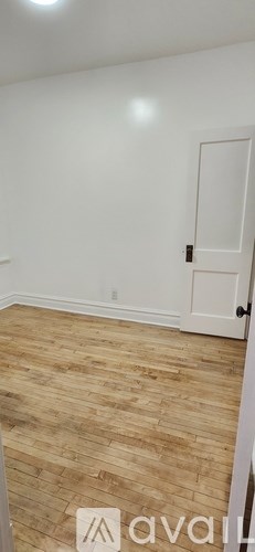 A room with wooden flooring and a white door.