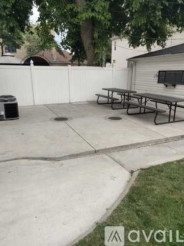 A patio with a table and chairs and a trash can.