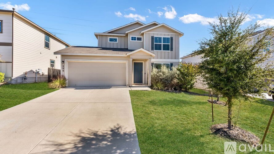 A house with a garage and a tree in front.