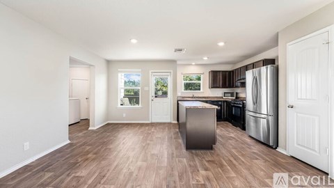 A kitchen with a refrigerator, oven, and microwave in a room with wooden flooring.