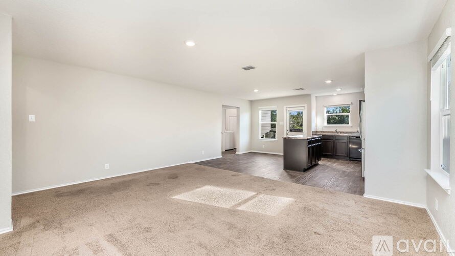 A spacious living room with a kitchen area in the background.