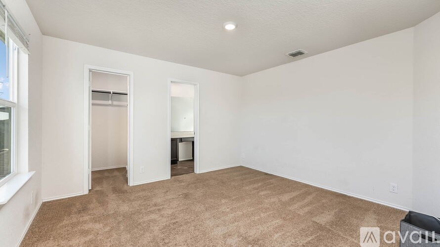 A carpeted room with a window on the left and a door on the right.