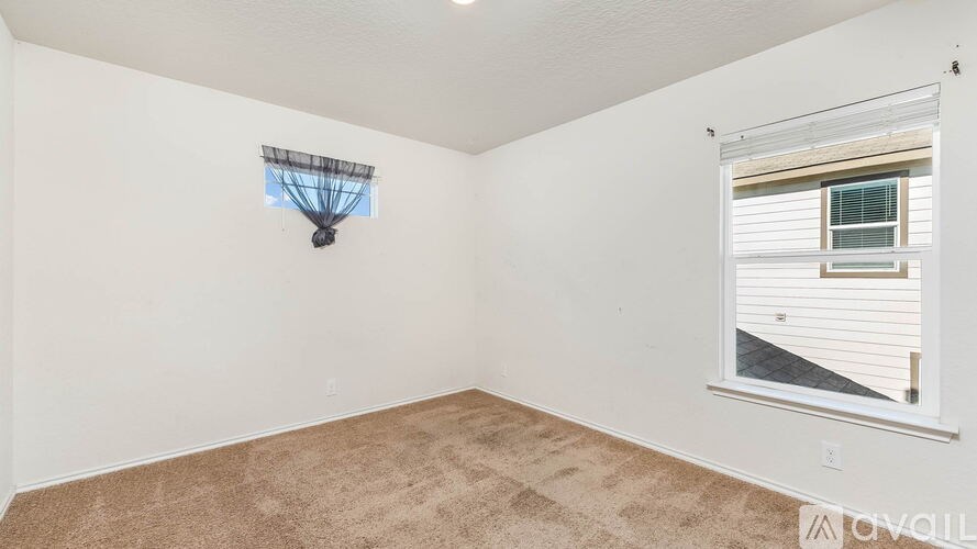 A room with a carpeted floor and a window with blinds.