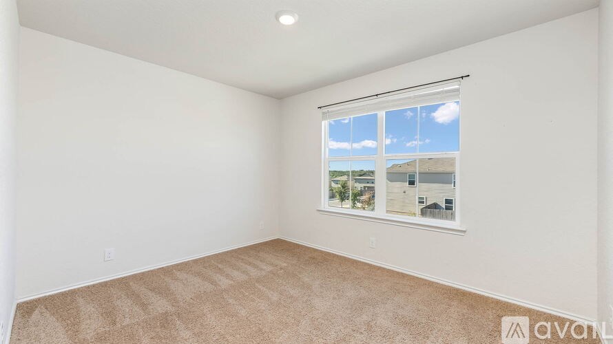 A room with a carpeted floor and a window showing a view of the outside.