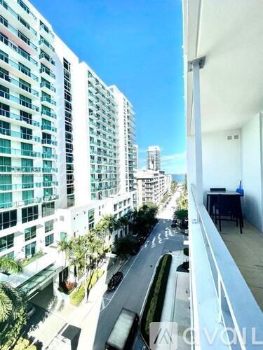 A balcony overlooks a city street with palm trees and buildings.