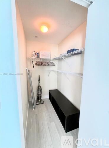 A small, white closet with a bench and a coat hanger.
