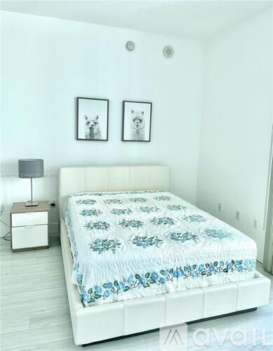 A bed with a white headboard and a blue and white comforter is in the image.