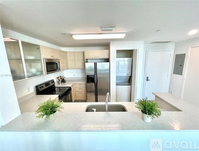 A kitchen with a refrigerator, sink, and microwave.