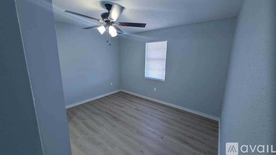 A room with a ceiling fan and wooden flooring.