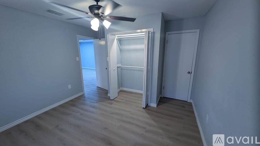 A room with a ceiling fan and a doorway leading to another room.