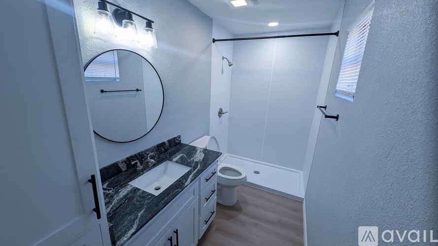 A bathroom with a marble countertop and a round mirror.